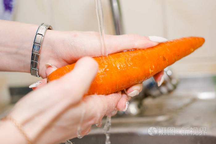 那个女孩洗胡萝卜用水从污垢中清洗胡萝卜