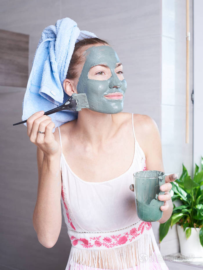 女人敷面膜保湿护肤霜在脸上看浴室镜子.