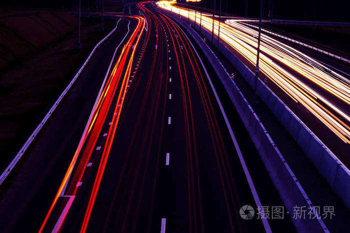 汽车在夜间在弯曲的公路上轻步夜间交通通道动作模糊夜间城市道路与