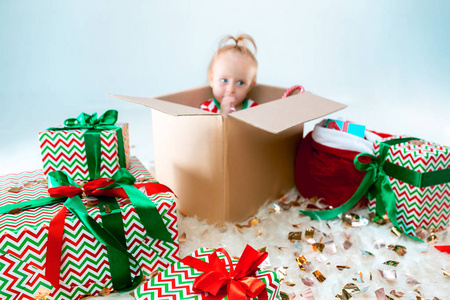 可爱的女婴1岁坐在盒子在圣诞节背景。节日