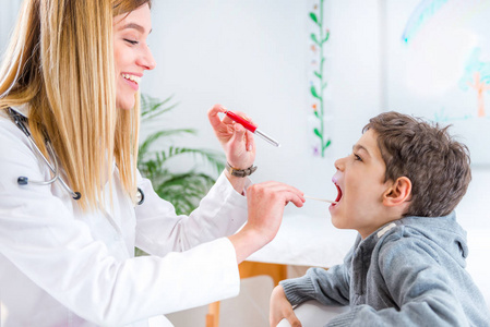 小儿科医生用笔炬检查男童喉和舌压缩器