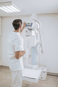 一名年轻的医疗技术人员在诊所操作X射线机器的后拍。