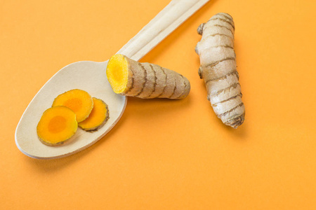 姜黄根与姜在木制勺子橙色背景