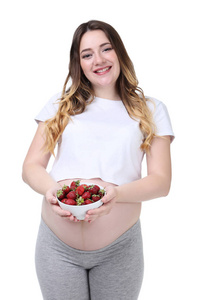 美丽的孕妇拿着碗，上面有白色背景的草莓
