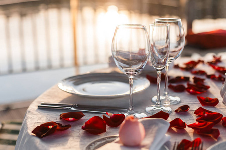浪漫的情人节晚餐，日落时配上玫瑰花瓣和空酒杯