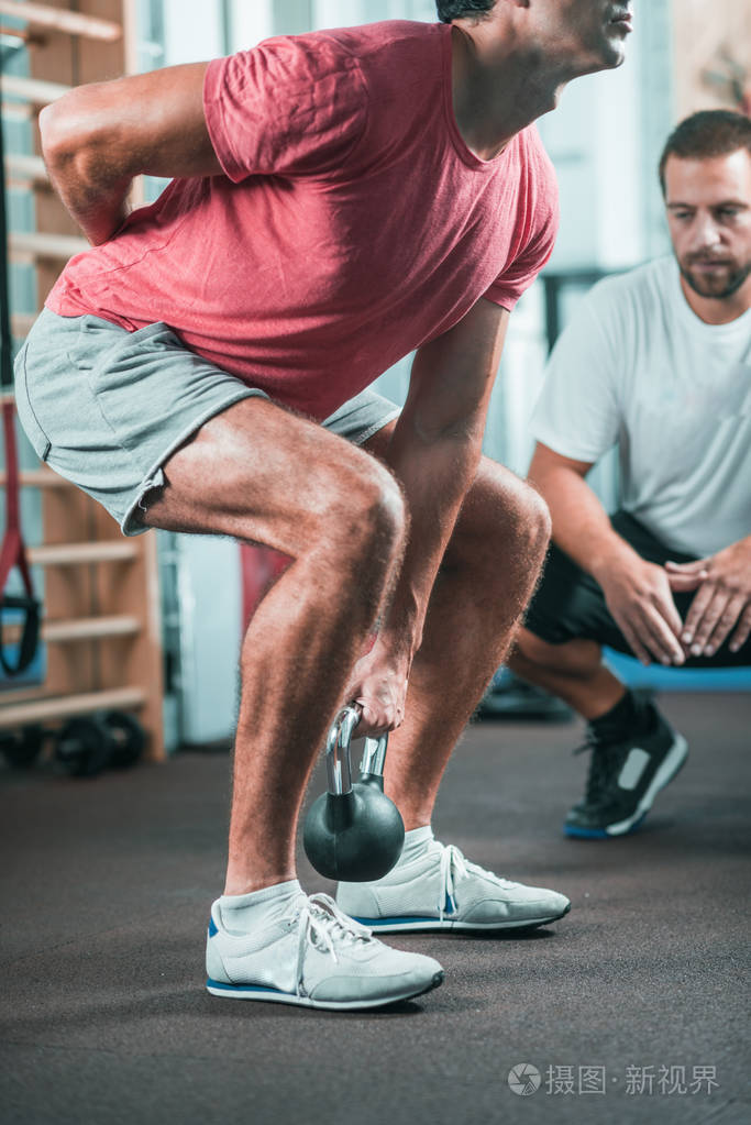 有男性客户在健身房锻炼的健身教练