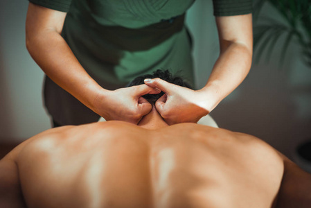 理疗师按摩颈部肌肉受伤的男性患者。 运动损伤治疗