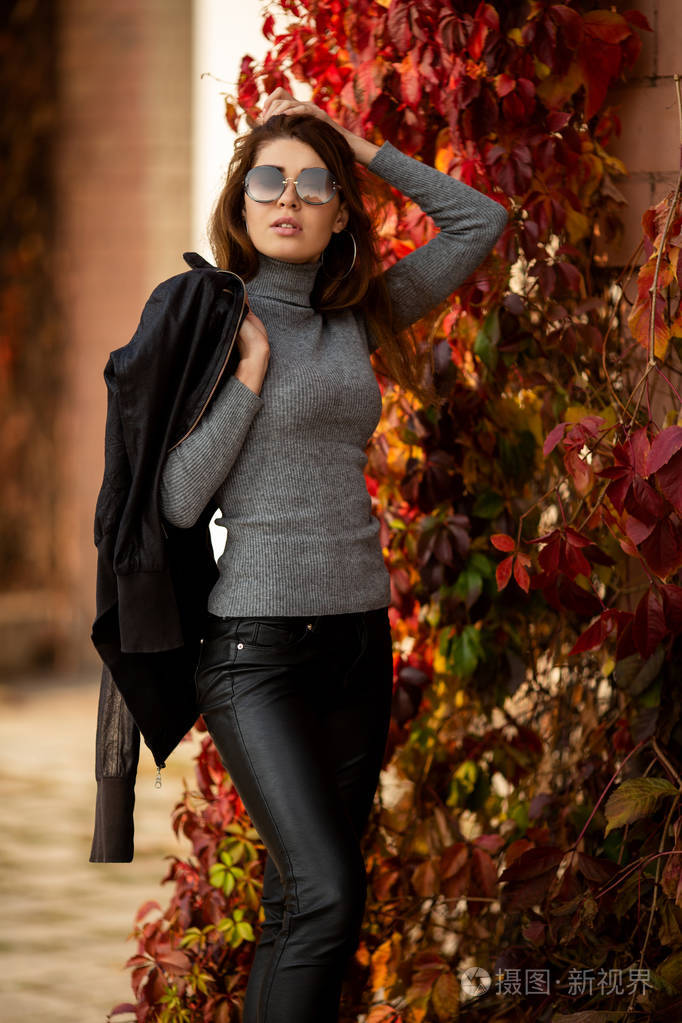 秋红常春藤背景下戴着太阳镜的长发妇女形象