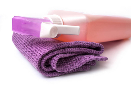白色背景下紫色清洁巾和喷雾瓶的特写