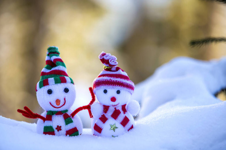 两个小有趣的玩具婴儿雪人在针织帽子和围巾在深雪户外明亮的蓝色和