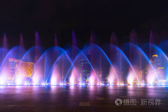 彩色的灯光和模糊的喷泉水显示在城市的黑色背景夜间