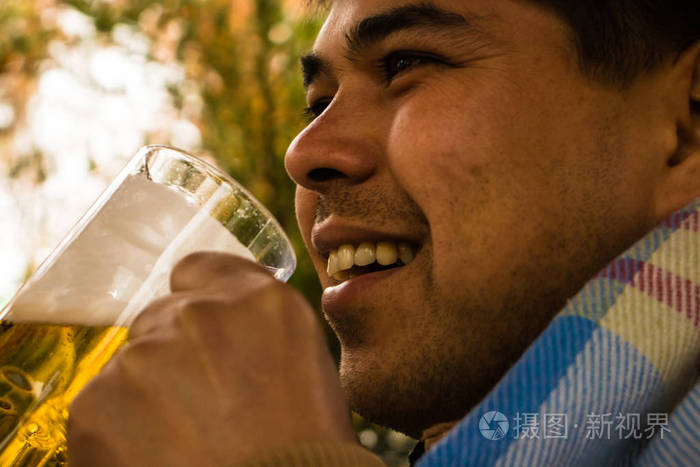特写一个男人喜欢在户外喝一杯啤酒的肖像。 秋天的气氛