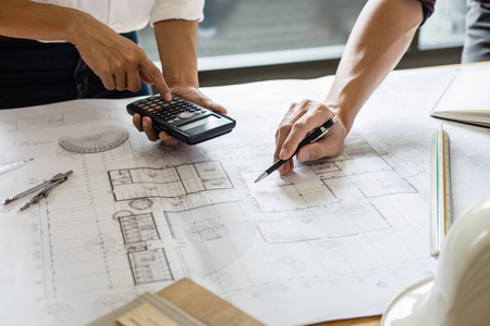 工程师或建筑师合作伙伴会议的形象，用于在工作空间的蓝图上检查建筑项目的建筑项目绘图和草图。