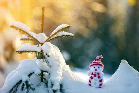 小有趣的玩具婴儿雪人在针织帽子和围巾在深雪户外明亮的蓝色和白色复制空间背景。 新年快乐，圣诞贺卡快乐。