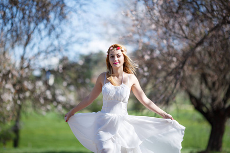 在盛开的花园里，年轻美丽浪漫的金发女子穿着白色连衣裙的模糊形象。