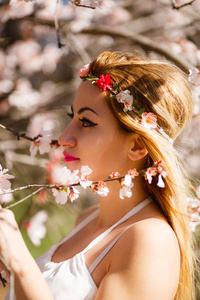 年轻美丽浪漫的金发女人穿着白色的裙子在盛开的花园里。