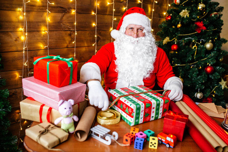 圣诞快乐, 节日快乐。圣诞老人正在家里的办公桌上为孩子们准备圣诞礼物