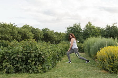 年轻快乐的运动女孩在城市公园慢跑后伸展身体