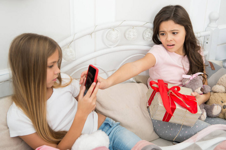 我不喜欢。小女孩在床上使用电话。用智能手机拍摄圣诞和新年照片。快乐的小孩用手机。圣诞快乐, 新年祝福