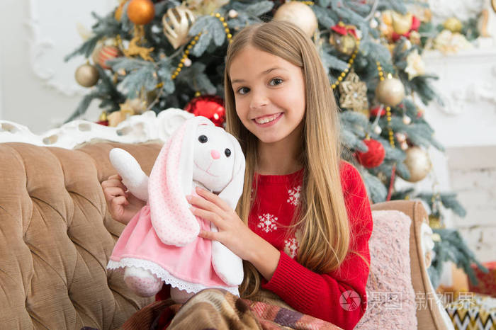 小孩子高兴地微笑着与礼物.小女孩与可爱的兔子在圣诞树上.