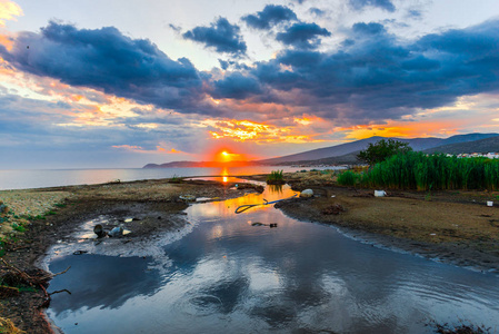 夕阳下空荡的海滨，隐藏着太阳和彩霞