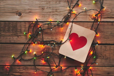 一张红心的卡片和一张木制桌子上的圣诞花环。