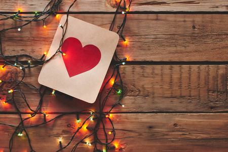 一张红心的卡片和一张木制桌子上的圣诞花环。