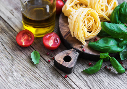 意大利食品配料意大利面西红柿罗勒和橄榄油放在旧木桌上