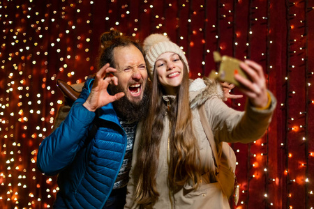 父亲和女儿在圣诞节市场开玩笑，自拍。
