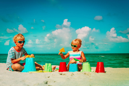 孩子男孩和女孩在沙滩上玩玩具
