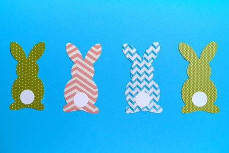 复活节兔子装饰在蓝色背景复制空间。 五颜六色兔子的DIY节日工艺品。 平躺顶部视图。 纸兔的边界。 复活节贺卡。 快乐复活节的概