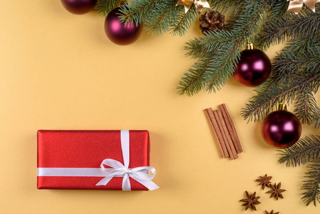 圣诞背景与红色礼品盒，杉树枝，玻璃球，松果，肉桂棒和星星八角在金色的背景自由空间。 平躺顶部视图，复制空间