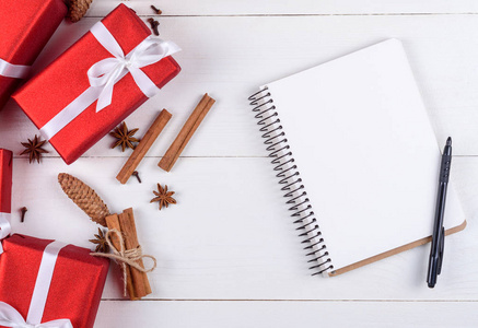 顶部查看红色圣诞礼品盒，杯可可和空白笔记本的目标或决议在白色木桌复制空间。 圣诞背景平版