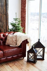 圣诞内饰与老式棕色皮革沙发冷杉树和灯笼在阁楼房间与全景窗口复制空间