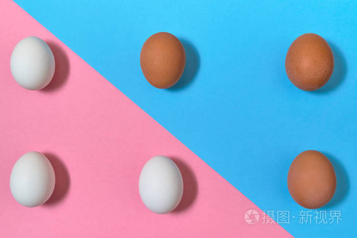 白色和棕色鸡蛋在蓝色和粉红色糊状背景复制空间。 煮鸡蛋在纸背景上，有两种色调。 健康的食物概念。 复活节彩蛋。 平躺式顶部视图