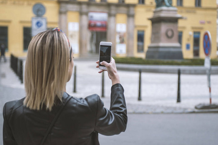 女游客在街上用手机拍照