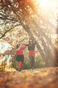 年轻时尚的母亲和女儿在温暖的秋日森林散步