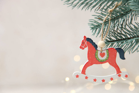 圣诞木制玩具形式的红色马重在枝状圣诞树上的中性模糊背景与灯光复制空间。