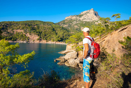 旅行者站在岩石上，欣赏地中海的绿松石水域，在阳光明媚的一天，冒险沿着荔枝之路土耳其旅行。 后景。