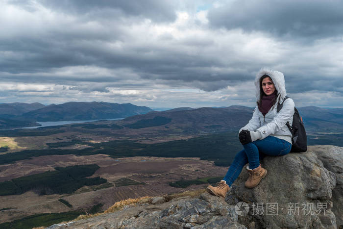 尼维斯山脉,一位身穿蓬松白色夹克衫,穿着徒步旅行鞋的女士山上摆姿势
