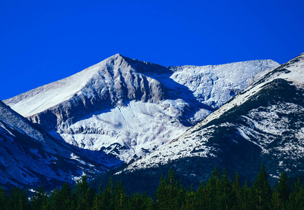 山峰雪山美丽的自然冬季背景。 山顶的冰蓝色天空背景。 高山景观林树线。