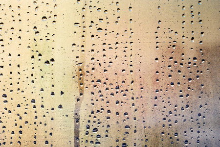 雨滴和冰冻的水落在窗户玻璃上,背景是金色和银色照片