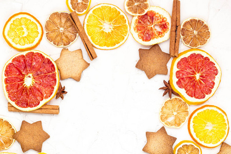 各种柑橘类水果姜饼和香料的干片的边缘，白色背景，带有铜空间。 圣诞框架