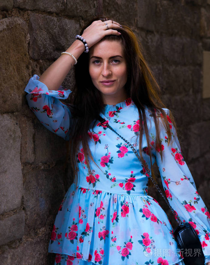 巴塞罗那砖墙附近的蓝色连衣裙的年轻女孩的肖像,主题是旅行暑假悄觋
