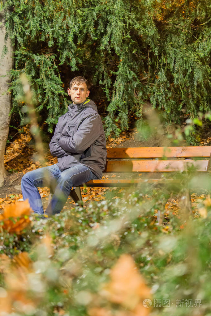 晚上坐在城市公园长凳上的年轻人的肖像