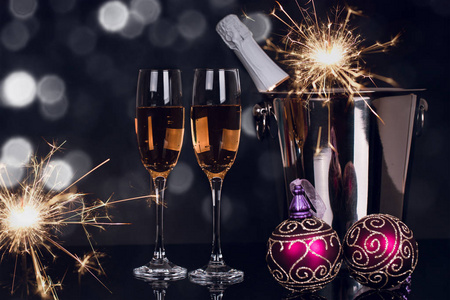 两个酒杯，香槟瓶，火花和圣诞装饰品在黑色背景。 复制空间。 圣诞快乐，新年快乐