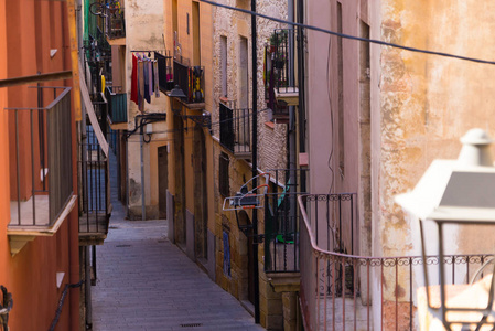 西班牙度假系列。 塔拉戈纳的狭窄街道。 黄砖墙和铺装人行道的旅游暑假。