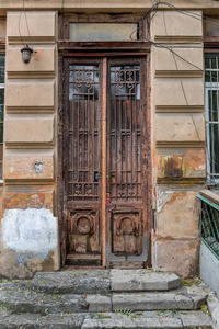 旧木门。 风化裂缝油漆，所以旧木门在一个古老的石头房子的墙上，在奥黛莎乌克兰的历史部分。 一堵旧的石墙，墙上贴着水泥，旧街门