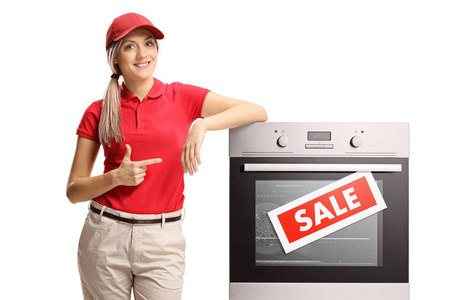 年轻的女售货员指着一个在白色背景下出售的电动烤箱
