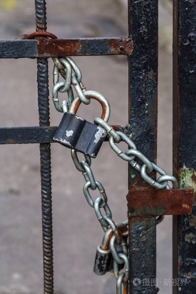 带有厚厚的金属链的大型五金挂锁重在铁门上. 铁门进了院子,关上了挂